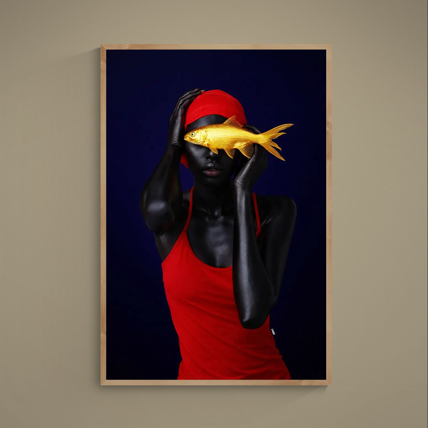 Surreal portrait poster with gold fish over the eyes, red cap and tank top on a deep navy background