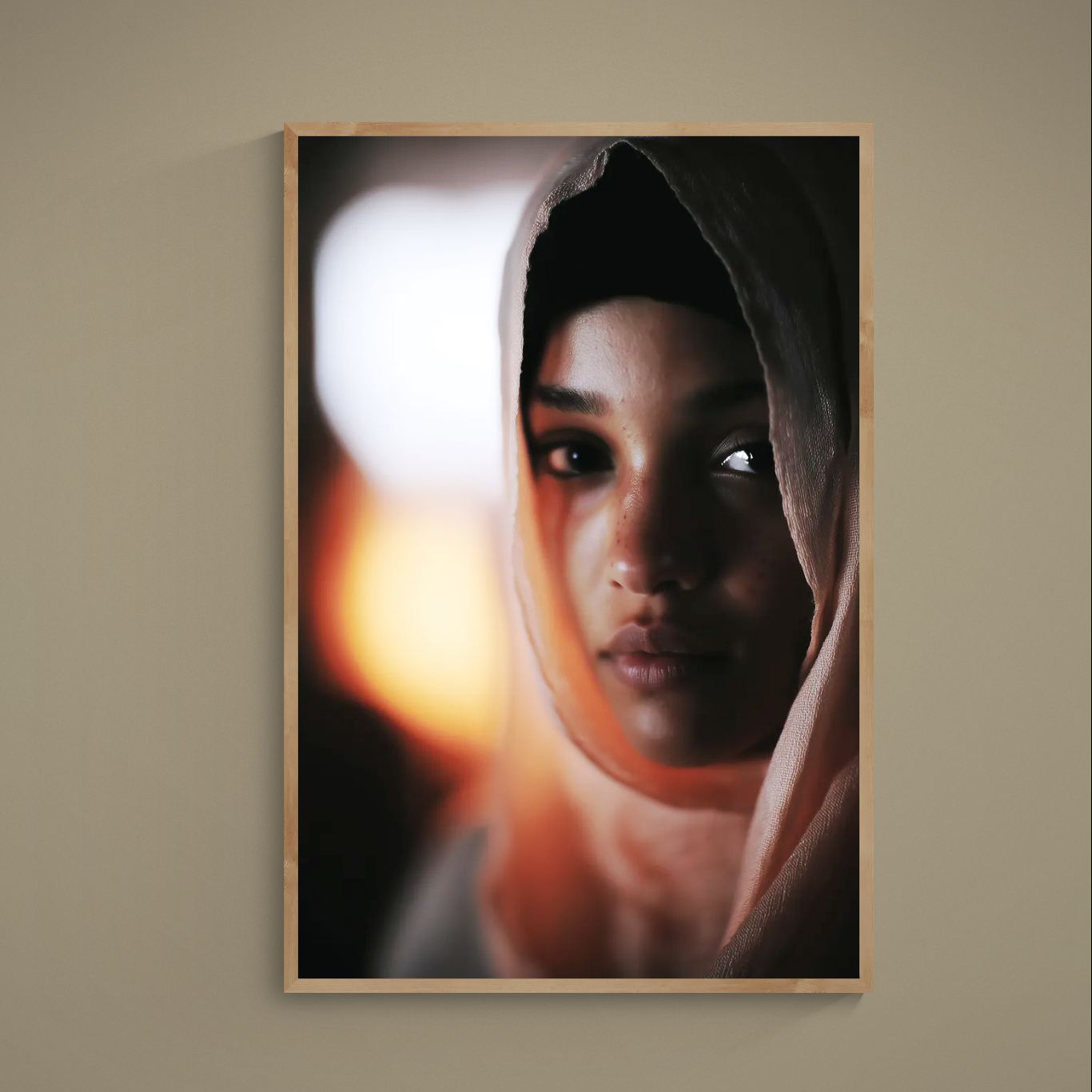 Close-up portrait of woman in beige hijab with deep shadows and warm orange bokeh background